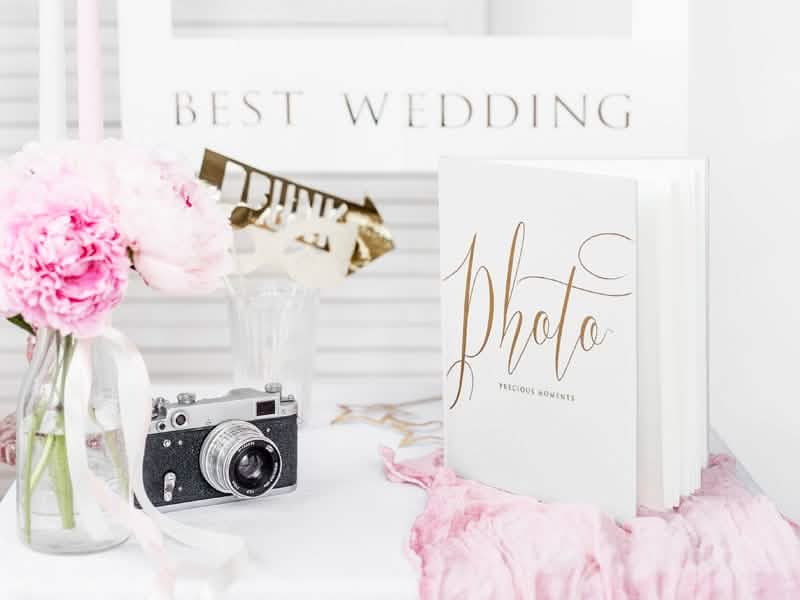Mise en scène avec accessoires et appareil photo de l'album photo mariage blanc et doré