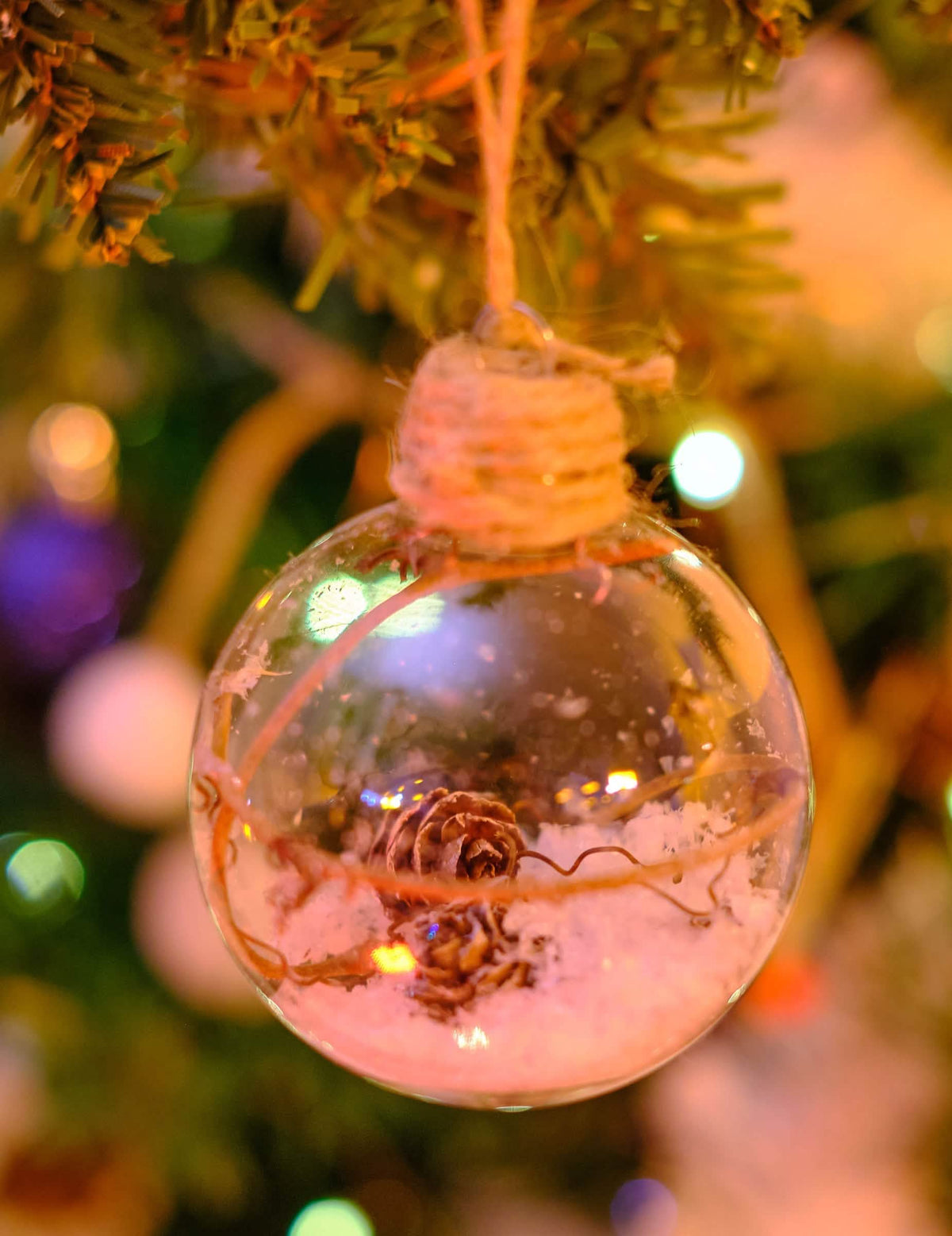 Mise en situation dans un sapin de la boule de Noël en verre avec pommes de pin et neige