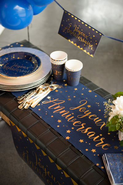 Mise en situation sur une table du chemin de table coton Joyeux anniversaire bleu marine et or