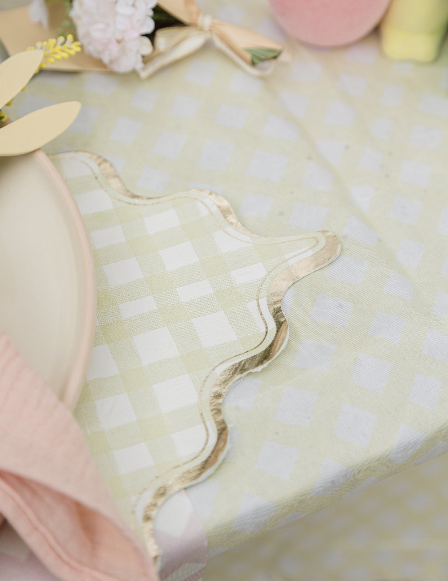 Gros plan sur la bordure dorée ondulée des serviettes en papier à motifs carreaux pour fête lilas rose jaune vert