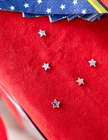 Vue de dessus des étoiles parsemées sur fond rouge du confettis de table étoiles miroir pour fête
