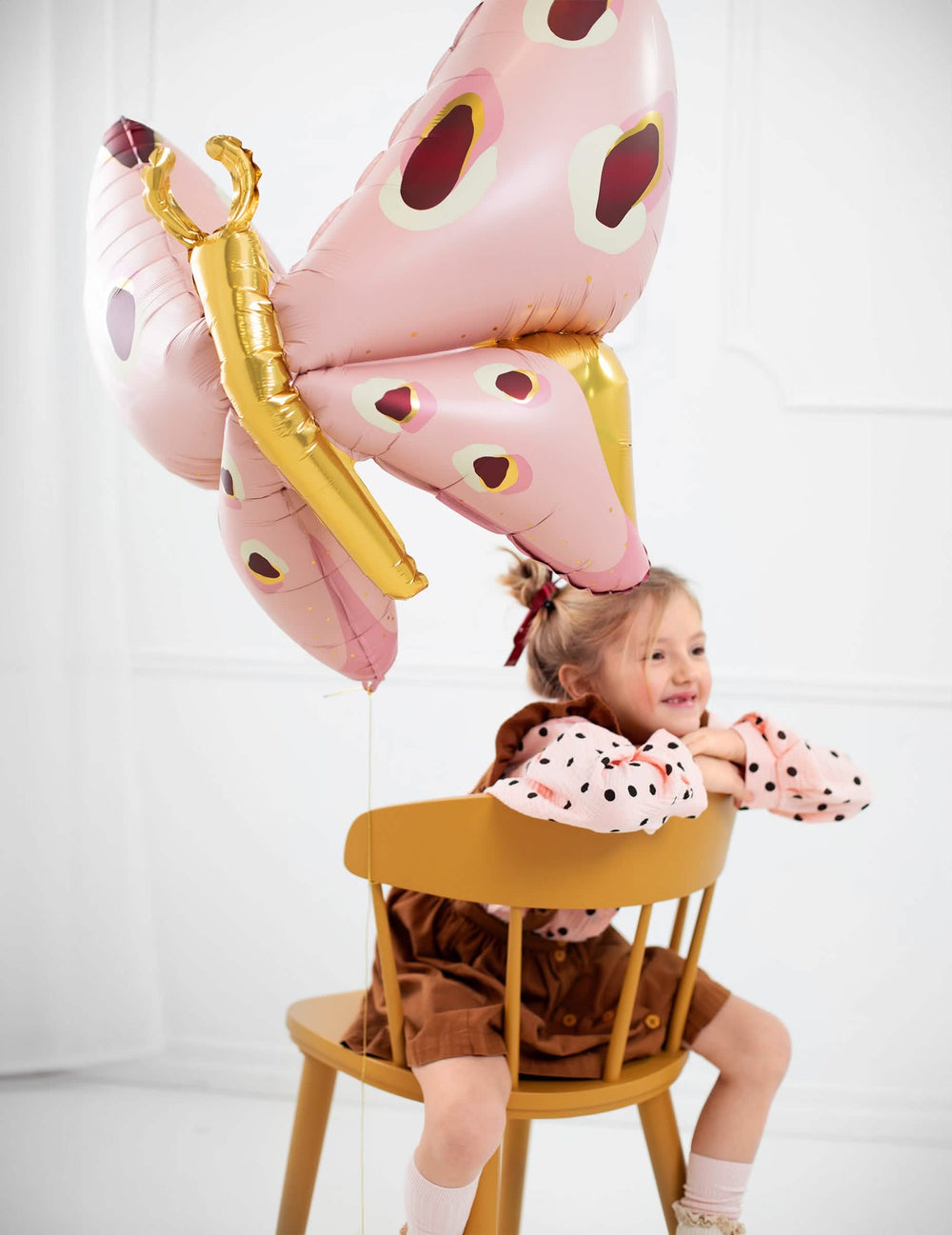 Mise en situation avec une enfant sur une chaise du ballon géant en aluminium papillon