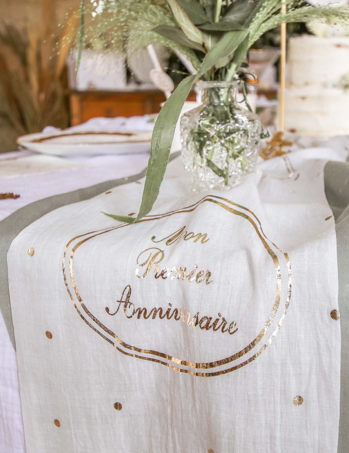 Détail de l'inscription dorée du chemin de table en gaze de coton Mon Premier Anniversaire
