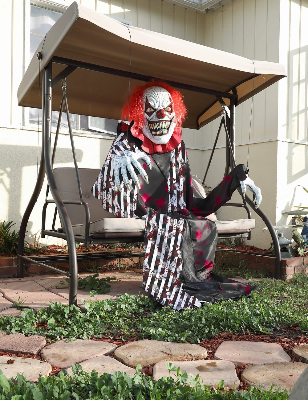 Zittende clown op een schommel van het angstaanjagende gigantische clownkostuum 2-in-1