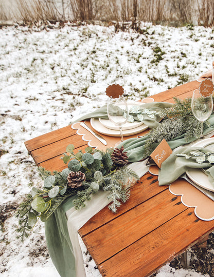 Mise en scène sur une table de fête de la descente de sapin et eucalyptus avec pommes de pin