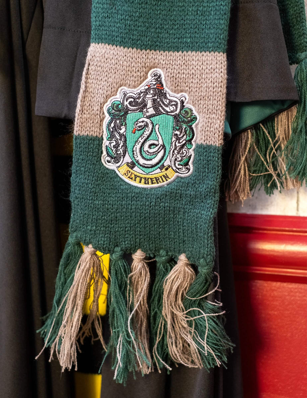 Zoom op het embleem en de pompon van de luxe Slytherin-sjaal