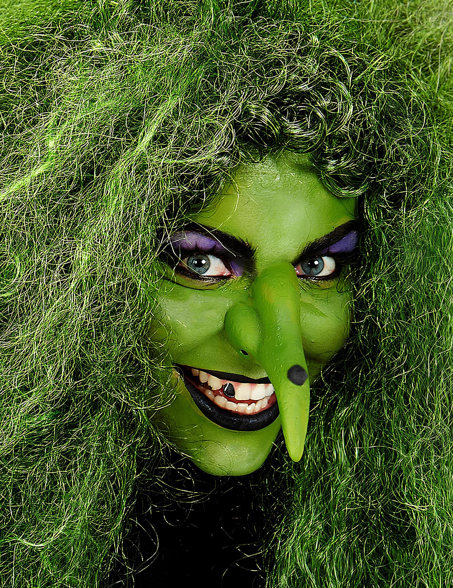 Gros plan sur le visage maquillé en sorcière du maquillage professionnel à l'eau pour visage et corps vert